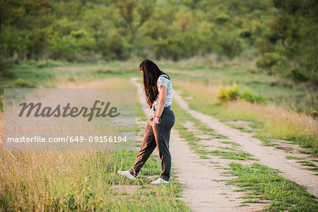 Young female tourist on dirt track in Kruger National Park, over shoulder view, South Africa