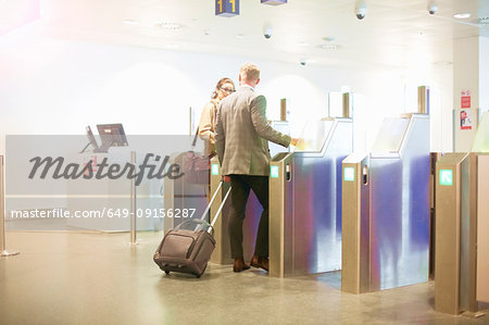 Businessman and woman walking through security gate at airport, low angle view