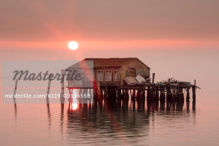 Old fishermen's shack at sunset in Venetian lagoon off the coast of Pellestrina, Venice, Veneto, Italy, Europe