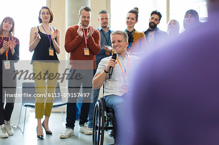 Audience clapping for female speaker in wheelchair