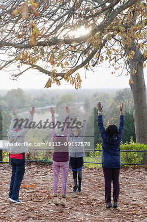 Active seniors practicing yoga, stretching in autumn park