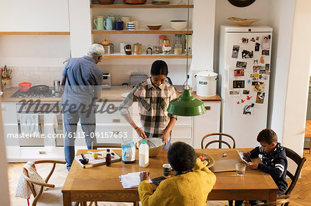 Grandparents and grandchildren baking and using digital tablet in kitchen