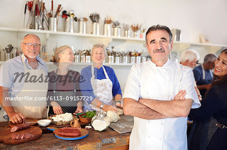 Portrait confident chef with senior students in cooking class kitchen