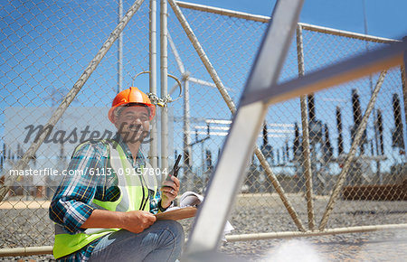Portrait smiling, confident male engineer with walkie-talkie at power plant