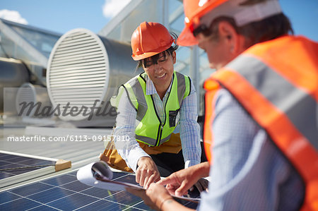 Engineers with clipboard examining solar panel at sunny power plant
