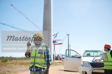 Male engineer with walkie-talkie at sunny wind turbine power plant