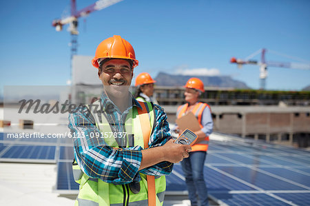 Portrait confident engineer installing solar panels on sunny rooftop Portrait confident engineer installing solar panels on sunny rooftop