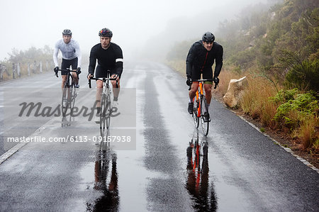 Male cyclists cycling on wet road