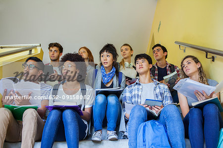 Group of students sitting on stairs, listening to informal presentation