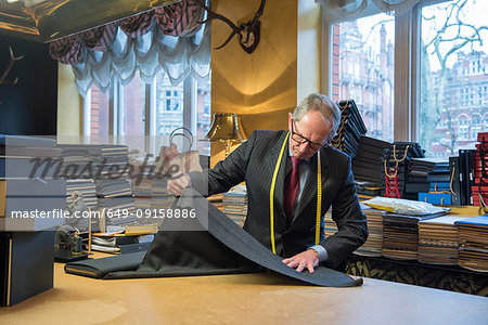 Tailor examining roll of cloth in tailor shop