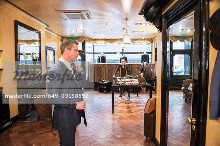 Male customer in full suit looking at mirror in tailors shop