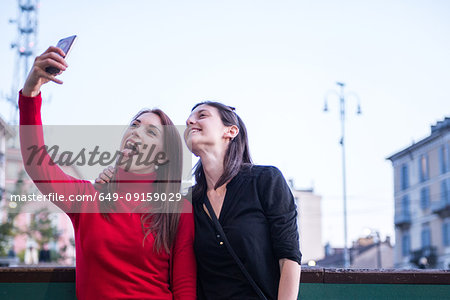 Young women taking selfie on bridge, Milan, Lombardy, Italy