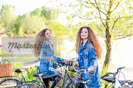 Fashion blogger twins with pushbikes by lake, Mantova, Lombardia, Italy Fashion blogger twins with pushbikes by lake, Mantova, Lombardia, Italy