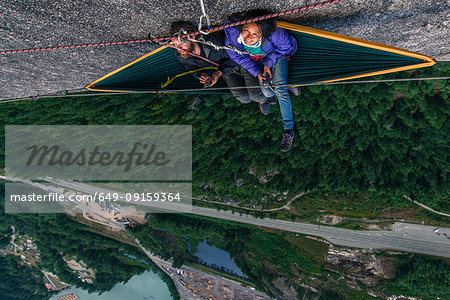 Man and woman sitting on hammock on bellygood ledge, The Chief, Squamish, Canada, overhead portrait