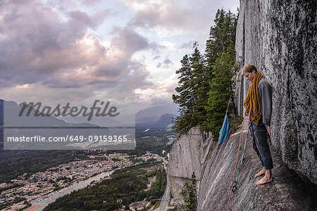 Young male climber standing barefoot on bellygood ledge, The Chief, Squamish, Canada