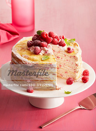 Raspberry crepe cake on a pedestal cake stand on a pink background