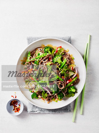 Soba noodle salad with chopsticks and chili flakes