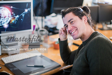 Portrait smiling, confident male graphic designer working at desk