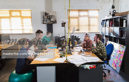 Creative business people working, meeting at computers in open plan office