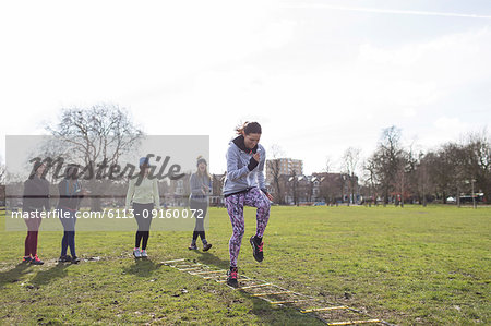 Focused woman doing speed ladder drill in sunny park