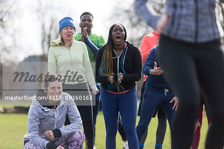 Team cheering woman exercising in park