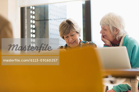 Senior businesswomen working at laptops in conference room meeting