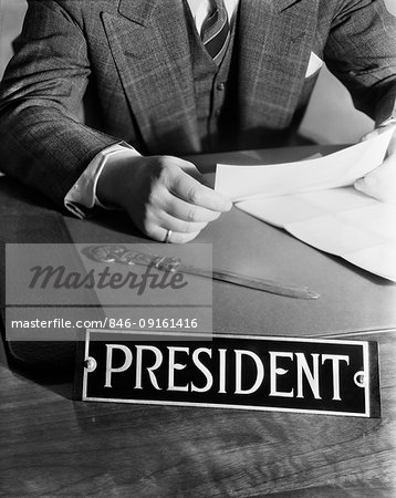 1930s 1940s 1950s MAN SITTING AT DESK READING LETTER WITH SIGN PRESIDENT