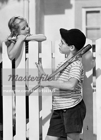 1940s 1950s BOY BASEBALL BAT CAP TALKING TO GIRL OVER WHITE PICKET FENCE