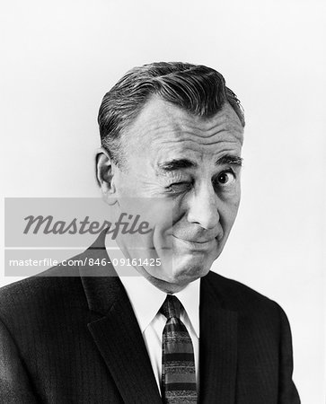 1950s PORTRAIT BUSINESS MAN LOOKING AT CAMERA WINKING HIS RIGHT EYE