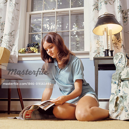 1970s TEENAGE GIRL SITTING ON FLOOR READING LIFE MAGAZINE