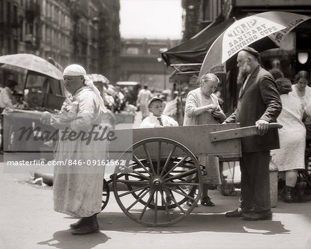 1930s DEPRESSION ERA LOWER EAST SIDE PUSHCART SCENE WITH EASTERN EUROPEAN IMMIGRANT VENDORS AND CUSTOMERS NEW YORK CITY USA