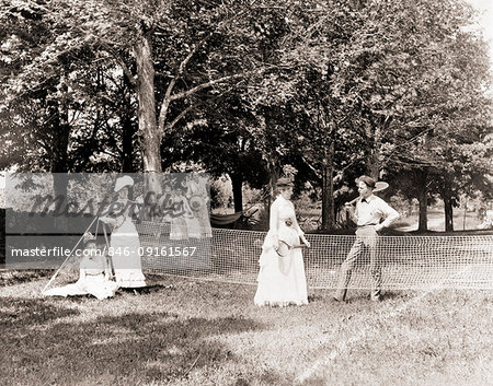 1890s 1900s GROUP OF MEN AND WOMEN GATHERED AROUND GRASS TENNIS COURT HOLDING RACQUETS