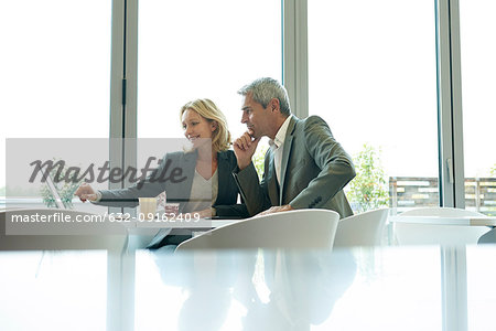 Businesspeople using laptop in cafeteria