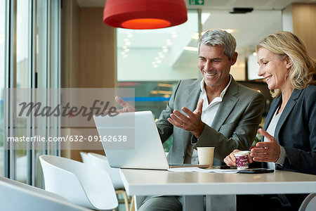 Businesspeople using laptop in cafeteria