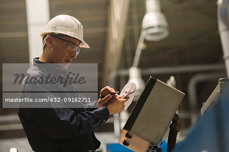 Factory worker examining control panel