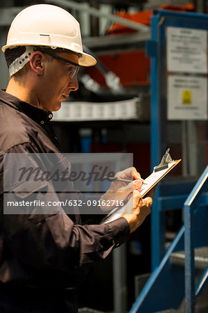 Factory working writing on clipboard