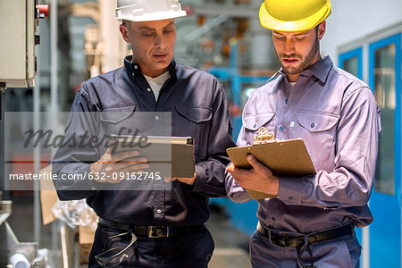 Factory workers with digital tablet and clipboard in factory