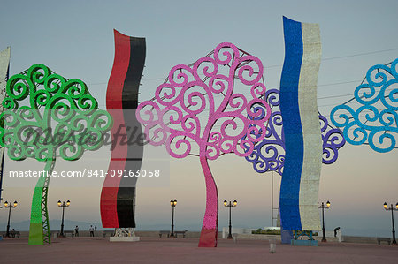 People in the evening by the lakeside malecon, with metal trees illuminated at night, Managua, Nicaragua, Central America