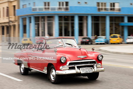 A red convertible vintage American car driving along the Malecon in Havana, Cuba, West Indies, Caribbean, Central America