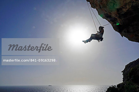Rock climber lowering off after ascending a steep climb on the cliffs of Malta, Mediterranean, Europe