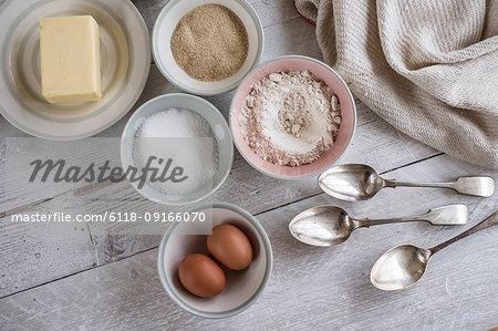 A table with ingredients for a baking project laid out, butter, sugar and flour, and two eggs.