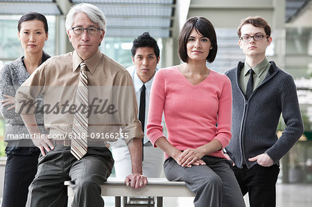 A team portrait of a mixed race group of business people with an Asian businessman in the lead.