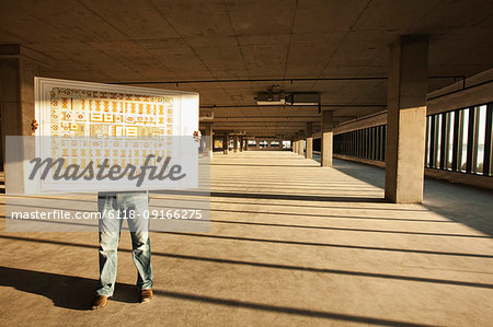 Businessman holding up plans for new office space standing in the middle of the empty raw space.