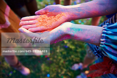 Young woman with cupped hands holding coloured chalk powder at Holi Festival, close up of hands