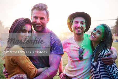 Four young adult friends covered in coloured chalk powder at Holi Festival, portrait