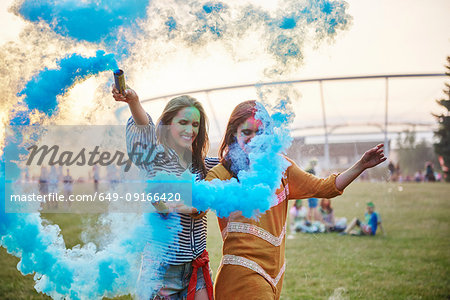 Two young women dancing with blue smoke bombs at Holi Festival