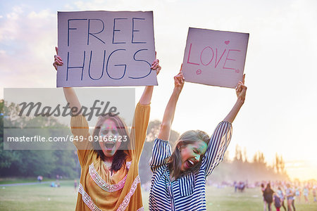 Young women dancing holding up love and free hug signs at Holi Festival