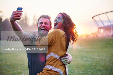 Young couple covered in coloured chalk powder taking selfie at Holi Festival
