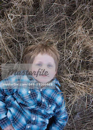 Boy lying in dry grass, portrait