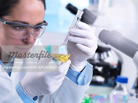 Scientist using flask to mix chemical compound during an experiment